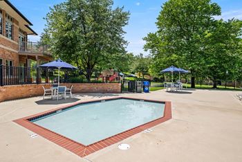 A small pool surrounded by a brick wall and trees.